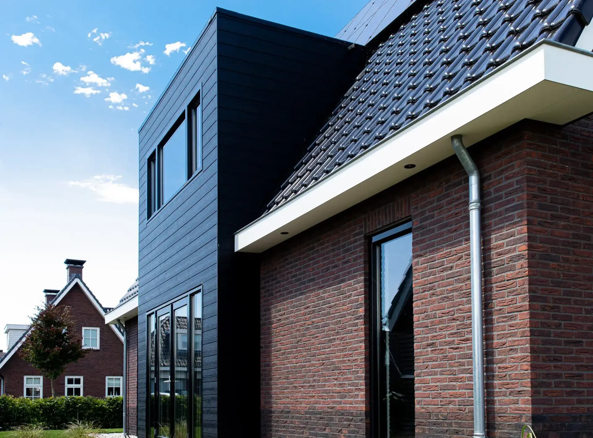 Traditionele T-kapwoning in Wolvega met klassieke materialen, een risaliet aan de tuinzijde en grote glasopeningen met uitzicht op het water.