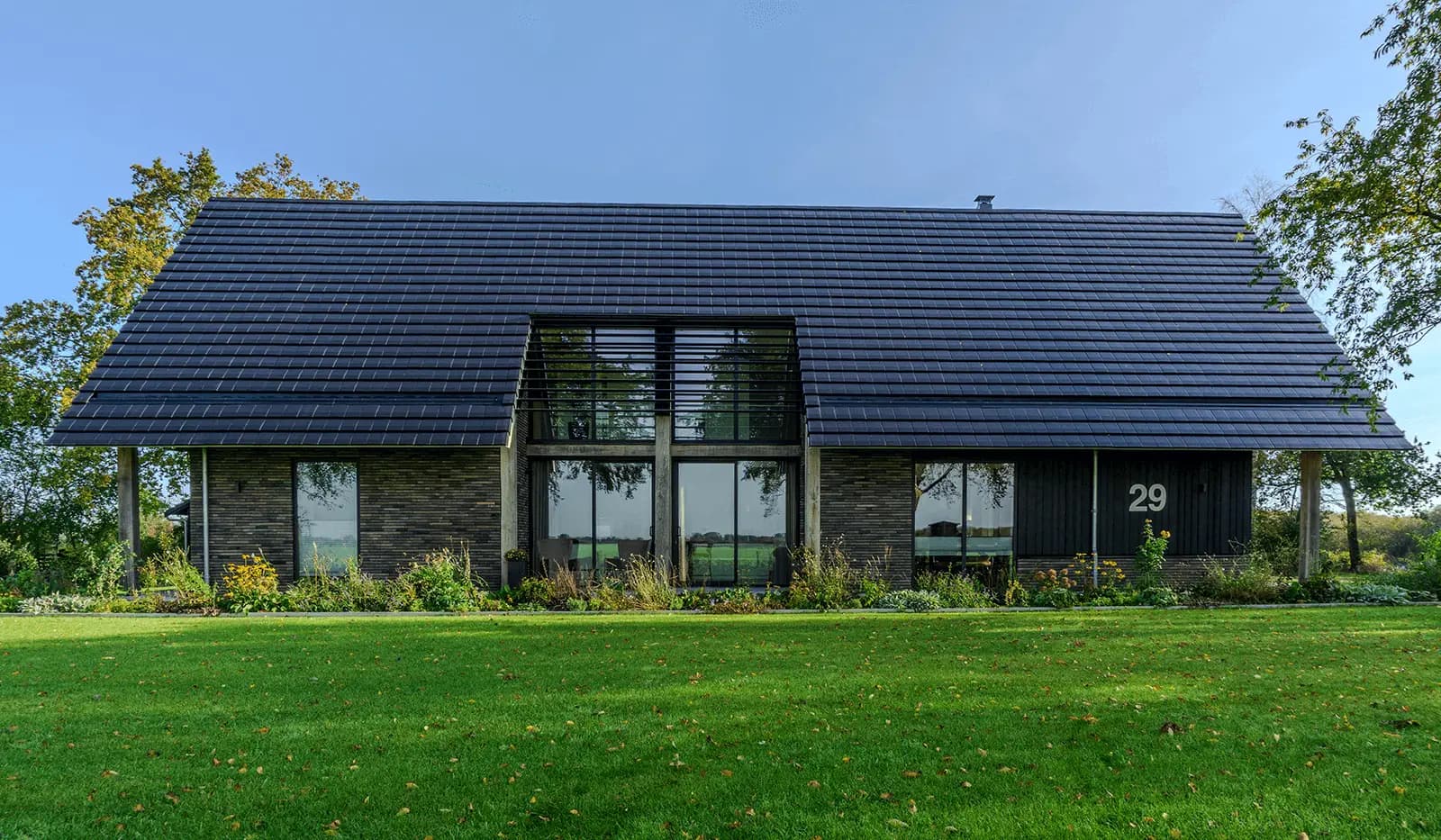 Moderne schuurwoning in Steggerda met open geveltop, houten spanten, donker metselwerk en royale glaspartijen — ontworpen door MArchitecten.