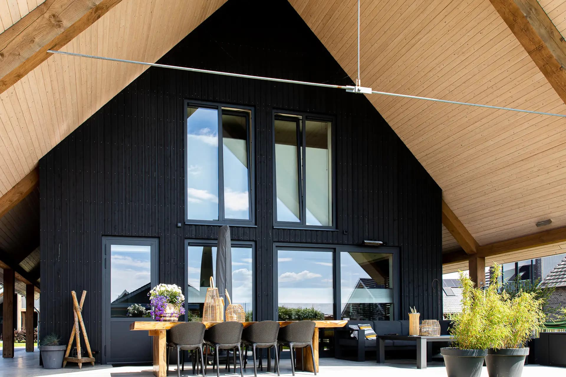 Schuurwoning in Wolvega met zwarte houten gevel, houten spanten en groot dakoverstek aan natuurgebied en water.