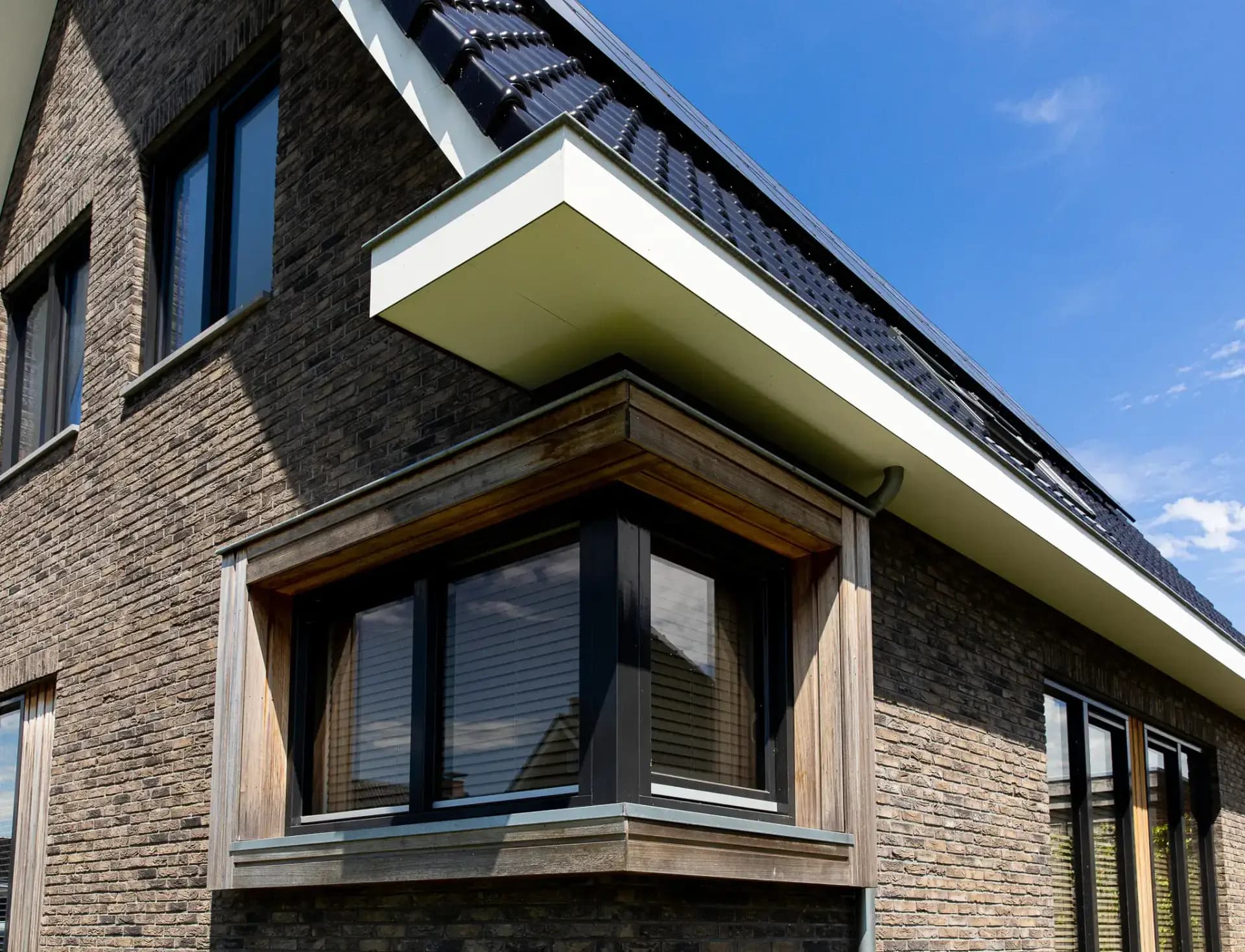 Traditioneel woonhuis Argusvlinder in Wolvega met klassieke gevel, zijbeuk en moderne kleurstelling — grote glaspartijen openen naar uitzicht op het water.