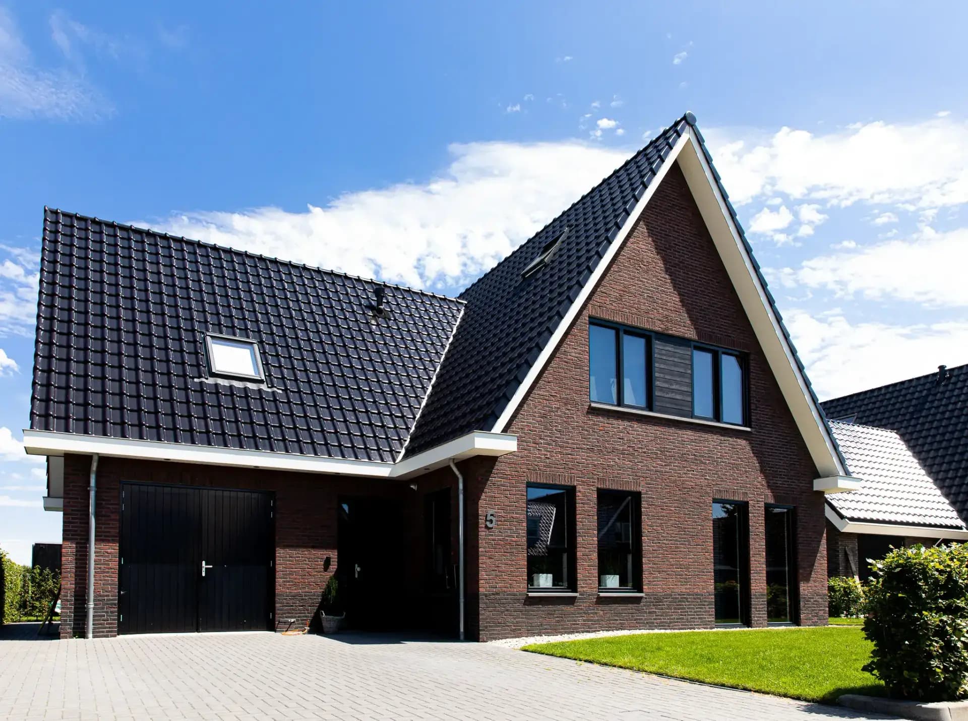 Traditionele T-kapwoning in Wolvega met klassieke materialen, een risaliet aan de tuinzijde en grote glasopeningen met uitzicht op het water.