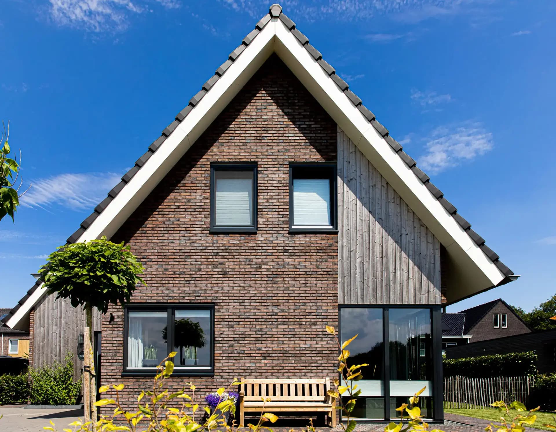 Parallelle kapwoning in Willemsoord met dubbele kapconstructie, twee nokken op één zakgoot, bruinrode baksteen en accenten in naturel hout.