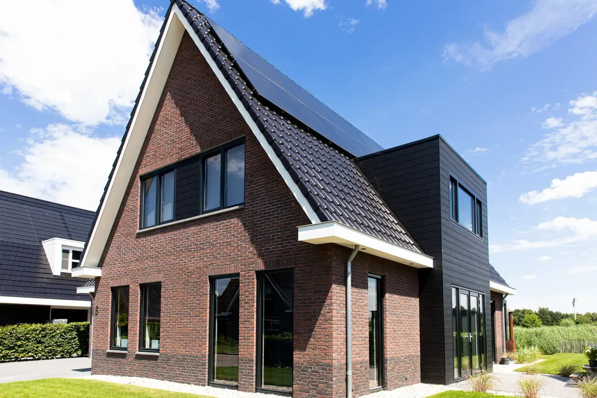 Traditionele T-kapwoning in Wolvega met klassieke materialen, een risaliet aan de tuinzijde en grote glasopeningen met uitzicht op het water.