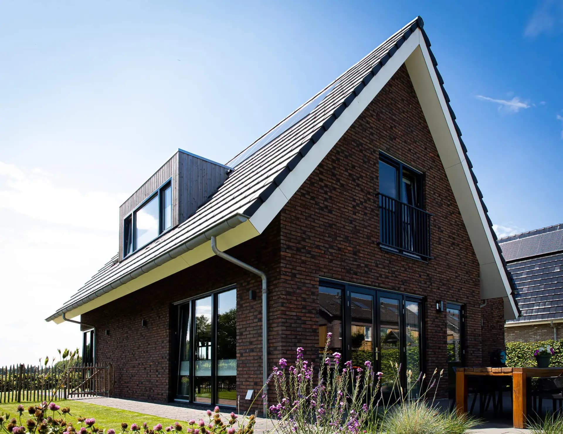 Parallelle kapwoning in Willemsoord met dubbele kapconstructie, twee nokken op één zakgoot, bruinrode baksteen en accenten in naturel hout.