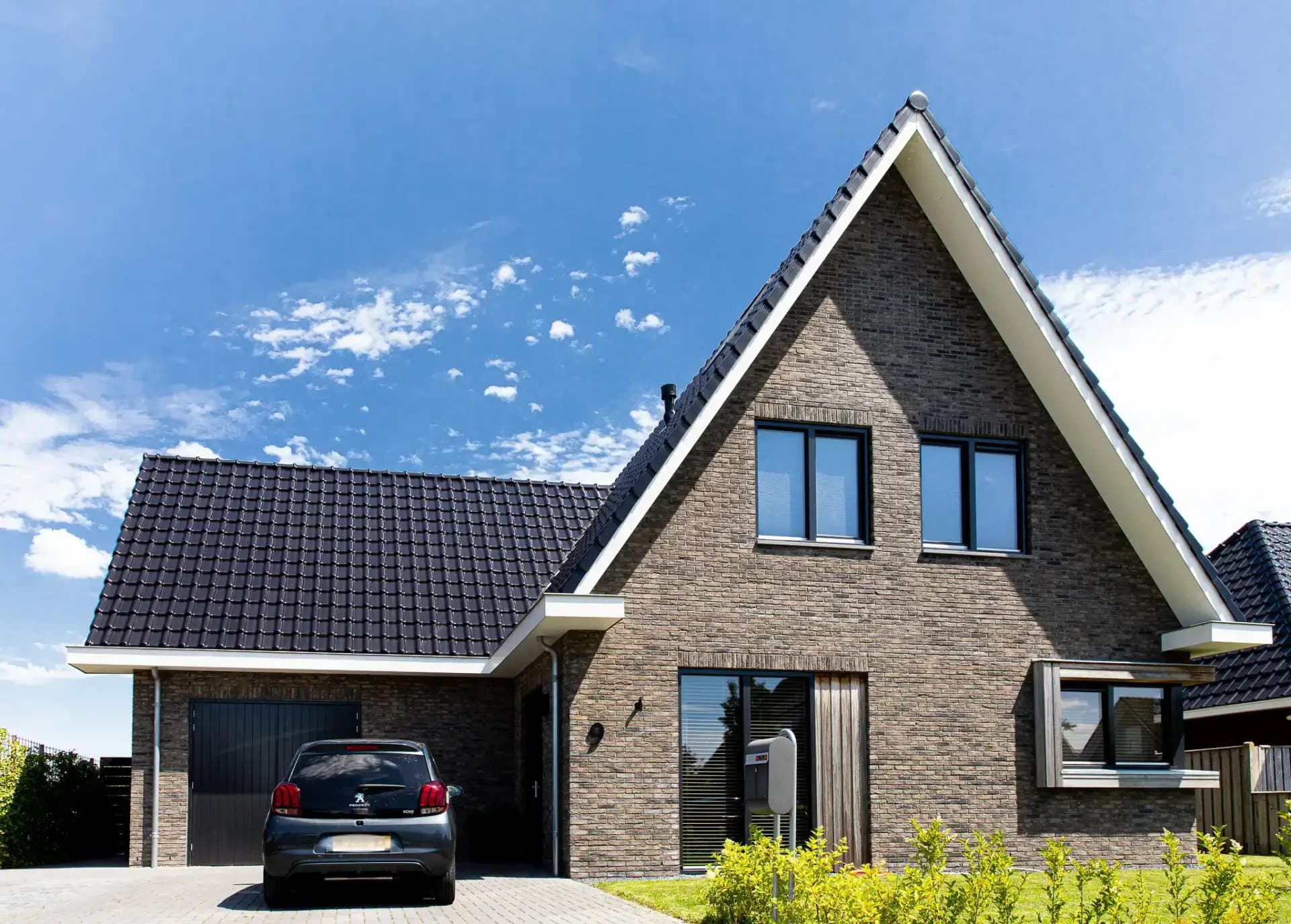 Traditioneel woonhuis Argusvlinder in Wolvega met klassieke gevel, zijbeuk en moderne kleurstelling — grote glaspartijen openen naar uitzicht op het water.