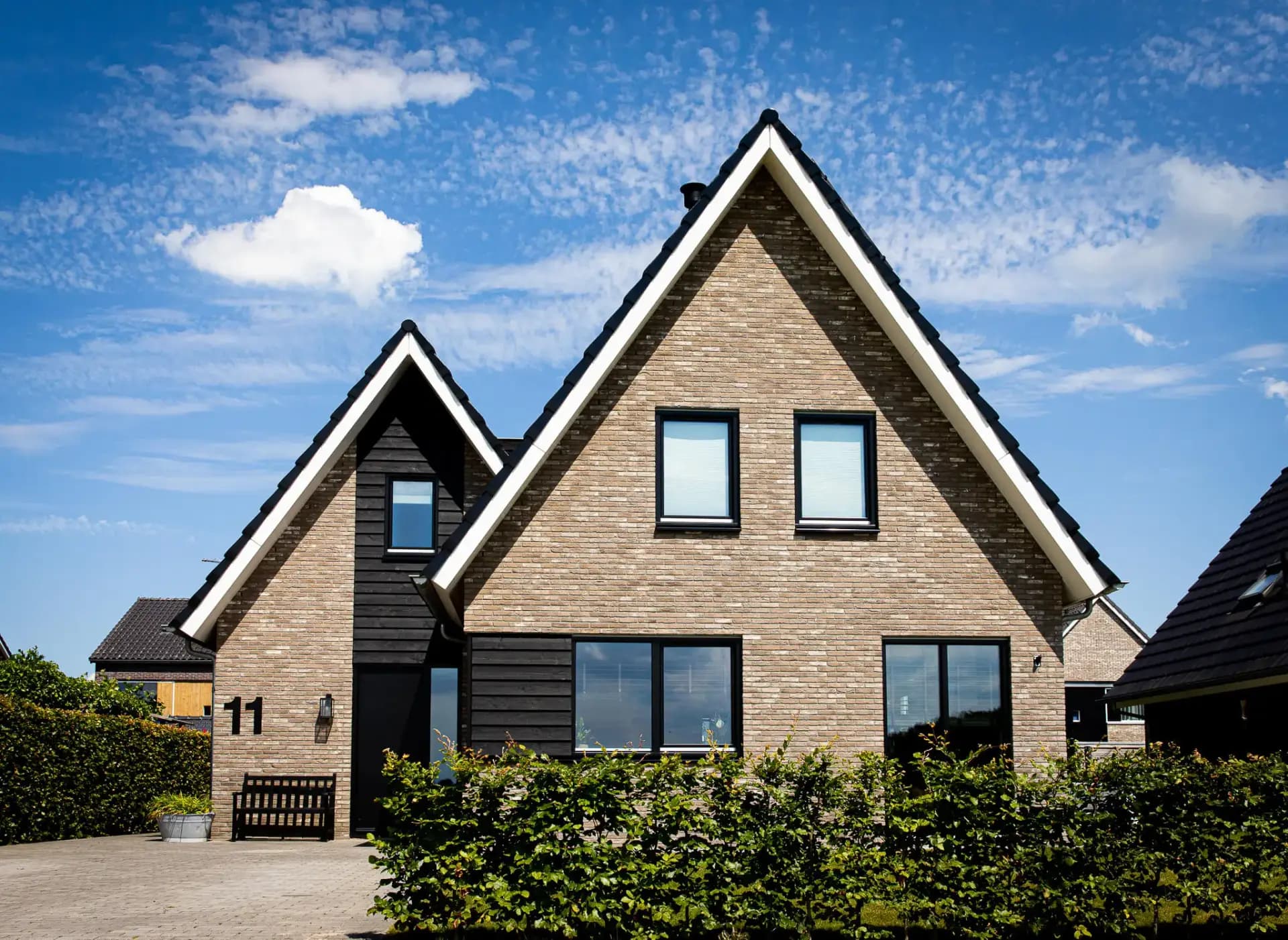 Woning in Willemsoord met dubbele kap, bronsgroen metselwerk en zwarte houten accenten — hedendaagse lintbebouwing.
