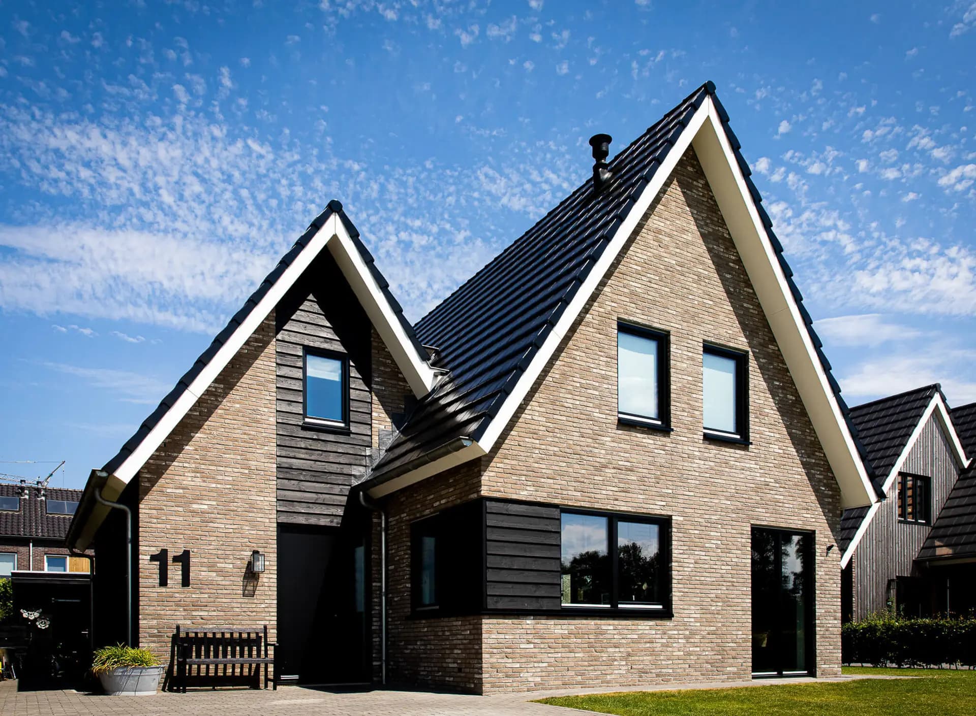 Woning in Willemsoord met dubbele kap, bronsgroen metselwerk en zwarte houten accenten — hedendaagse lintbebouwing.