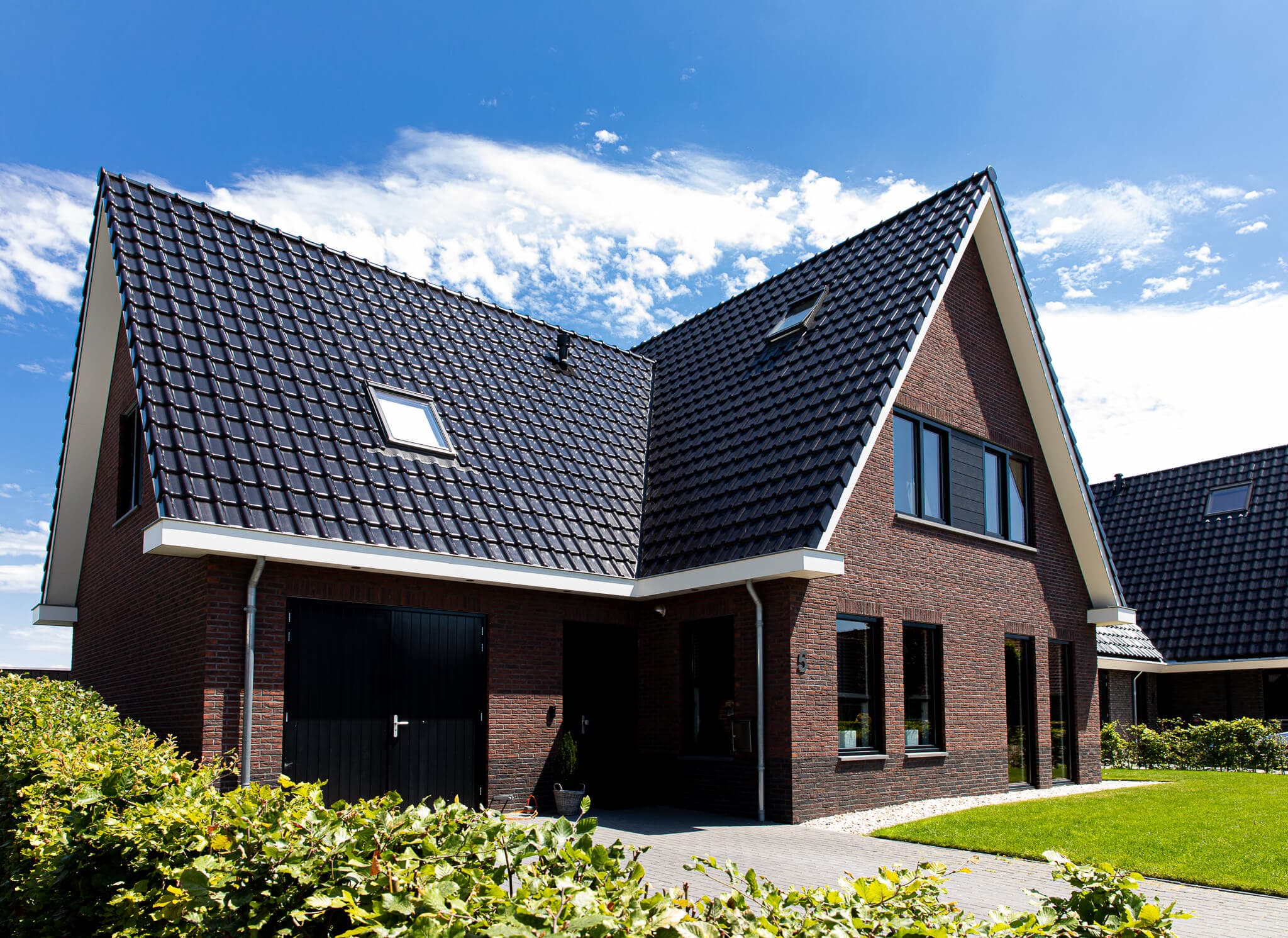 Traditionele T-kapwoning in Wolvega met klassieke materialen, een risaliet aan de tuinzijde en grote glasopeningen met uitzicht op het water.