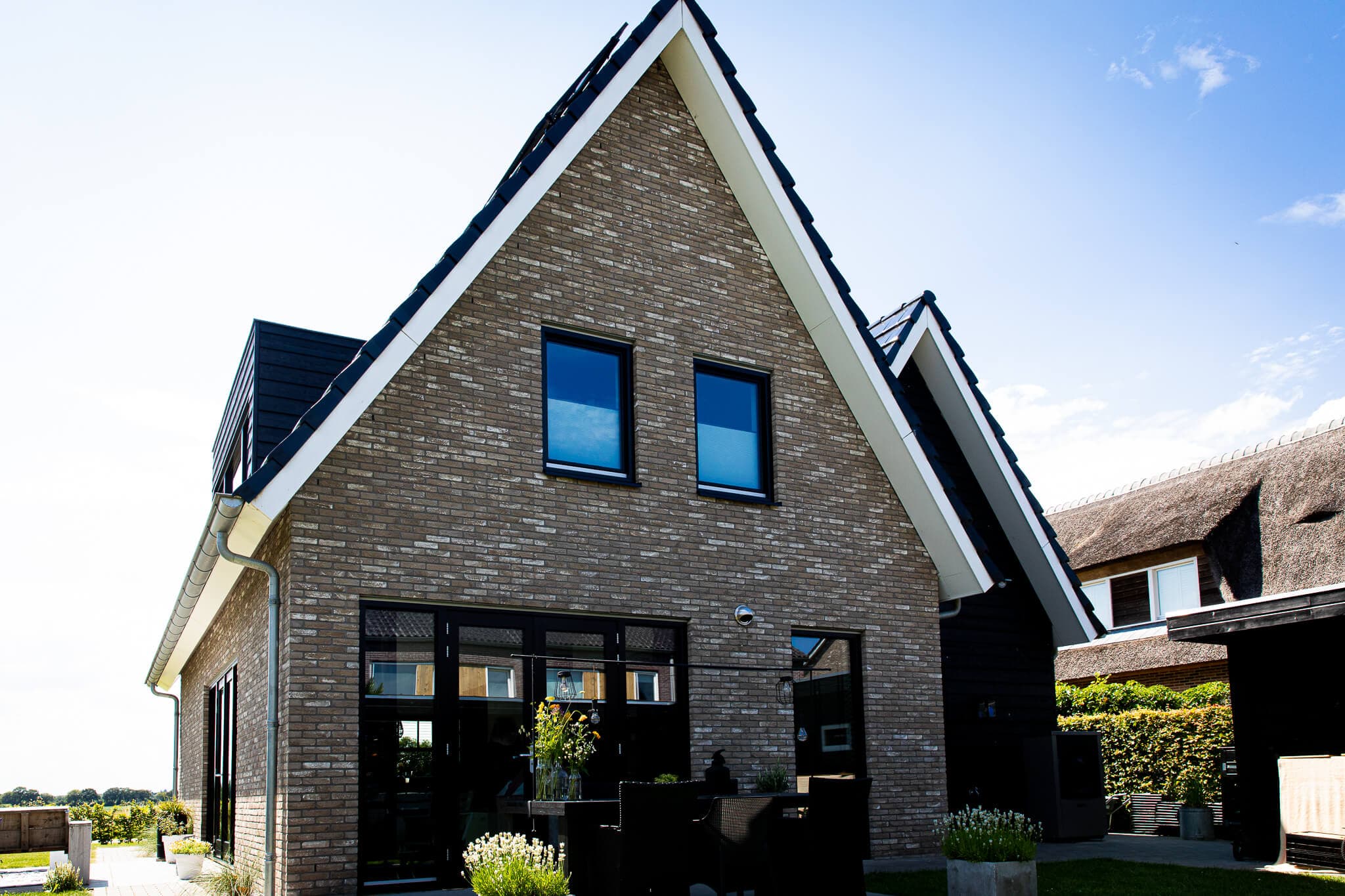Woning in Willemsoord met dubbele kap, bronsgroen metselwerk en zwarte houten accenten — hedendaagse lintbebouwing.