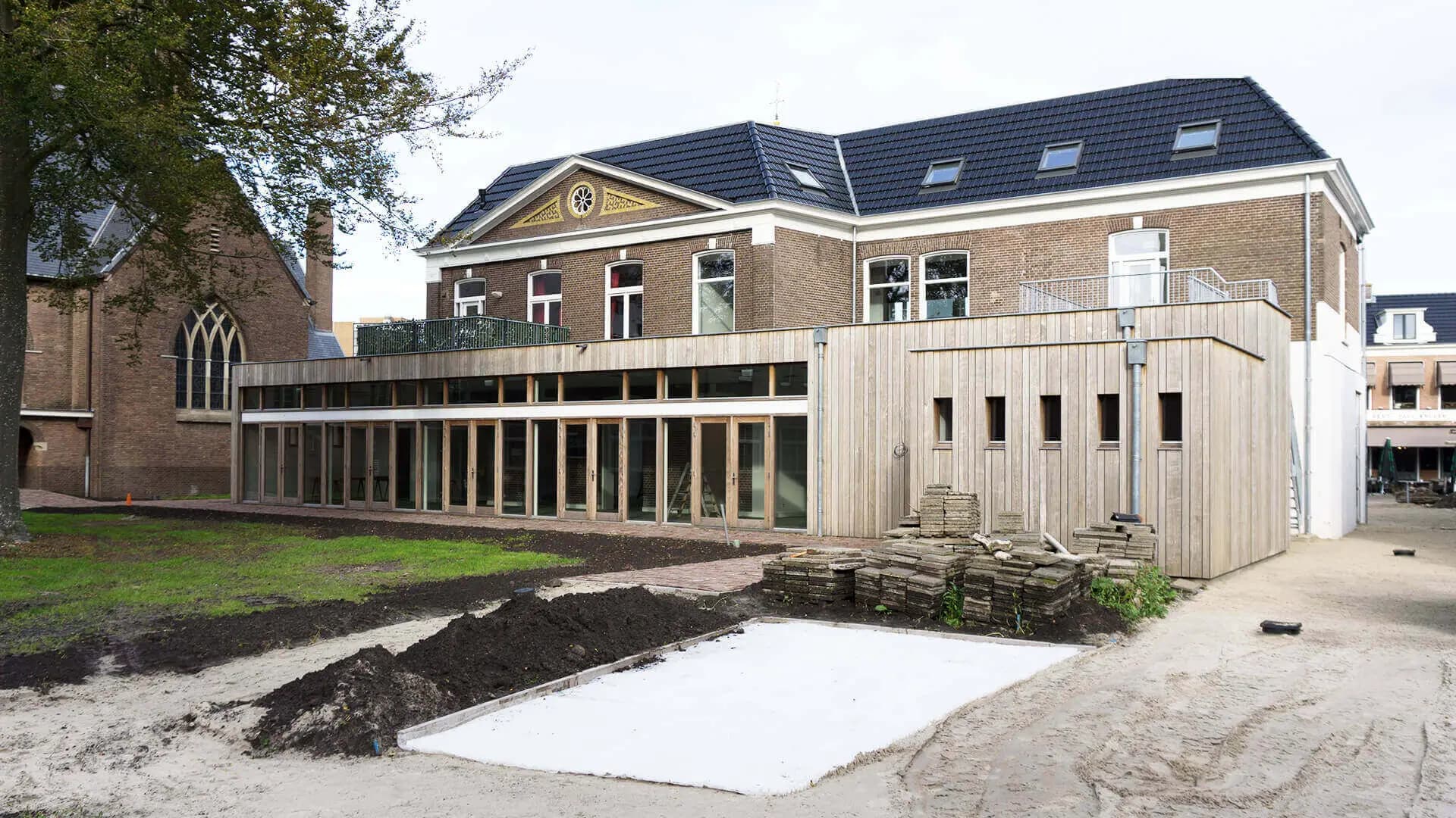 Renovatie van een laat negentiende-eeuws parochiecentrum aan de Crackstraat in Heerenveen, met nieuwe aanbouw, kloostergang en stads-kloostertuin.