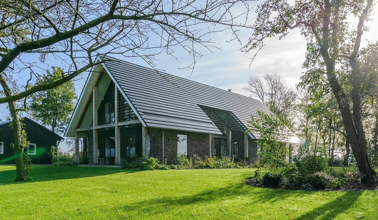 Moderne schuurwoning in Steggerda met open geveltop, houten spanten, donker metselwerk en royale glaspartijen — ontworpen door MArchitecten.