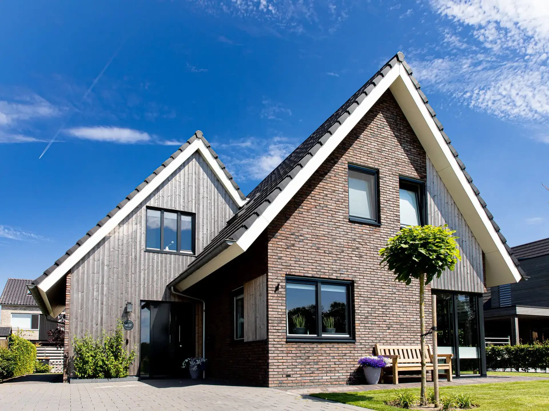 Parallelle kapwoning in Willemsoord met dubbele kapconstructie, twee nokken op één zakgoot, bruinrode baksteen en accenten in naturel hout.