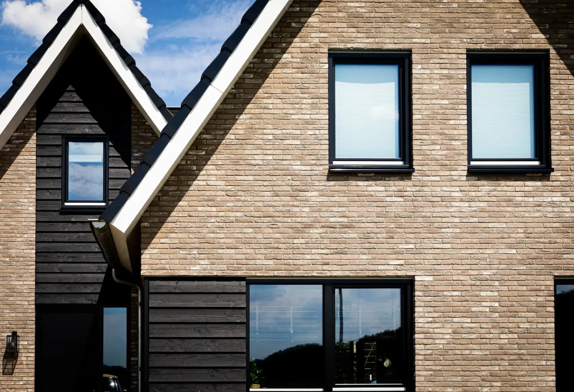 Woning in Willemsoord met dubbele kap, bronsgroen metselwerk en zwarte houten accenten — hedendaagse lintbebouwing.