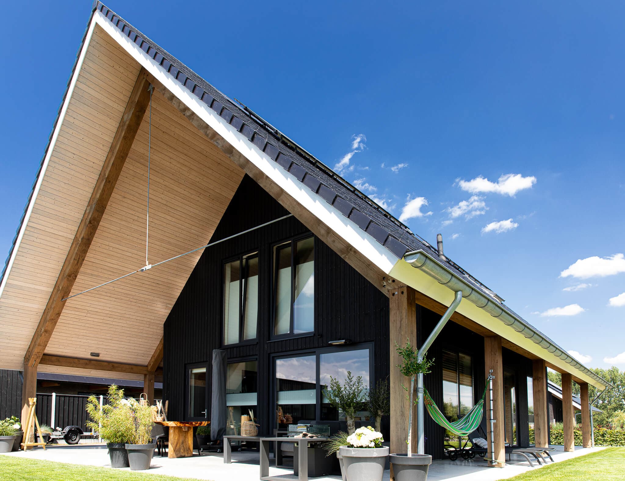 Schuurwoning in Wolvega met zwarte houten gevel, houten spanten en groot dakoverstek aan natuurgebied en water.