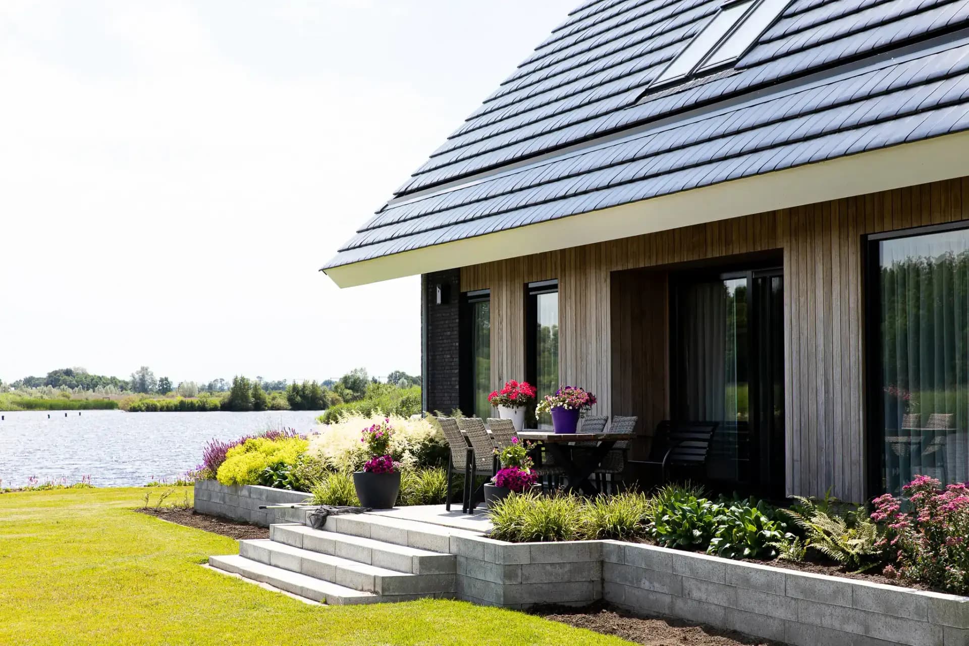 Schuurwoning op een kopkavel aan het Icarusblauwtje in Wolvega, in naturel hout met langformaat metselwerkaccenten en panoramisch uitzicht op het water.