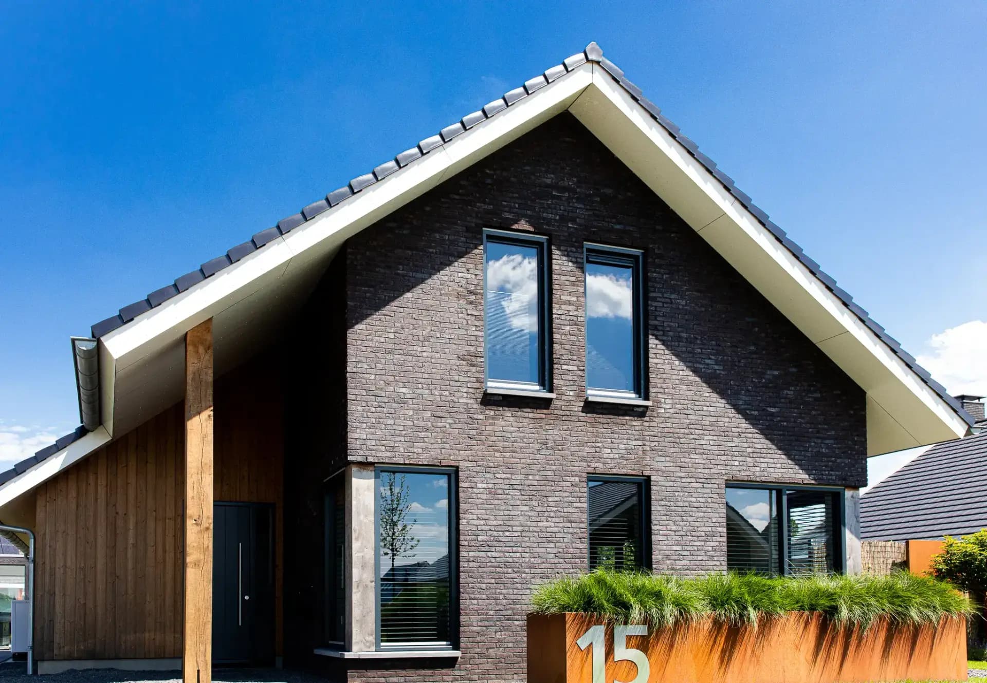 Vrijstaand modern woonhuis aan het Heideblauwtje in Wolvega (Lindewijk) met baksteen, houten accenten, leigrijze kozijnen en licht boeideel.