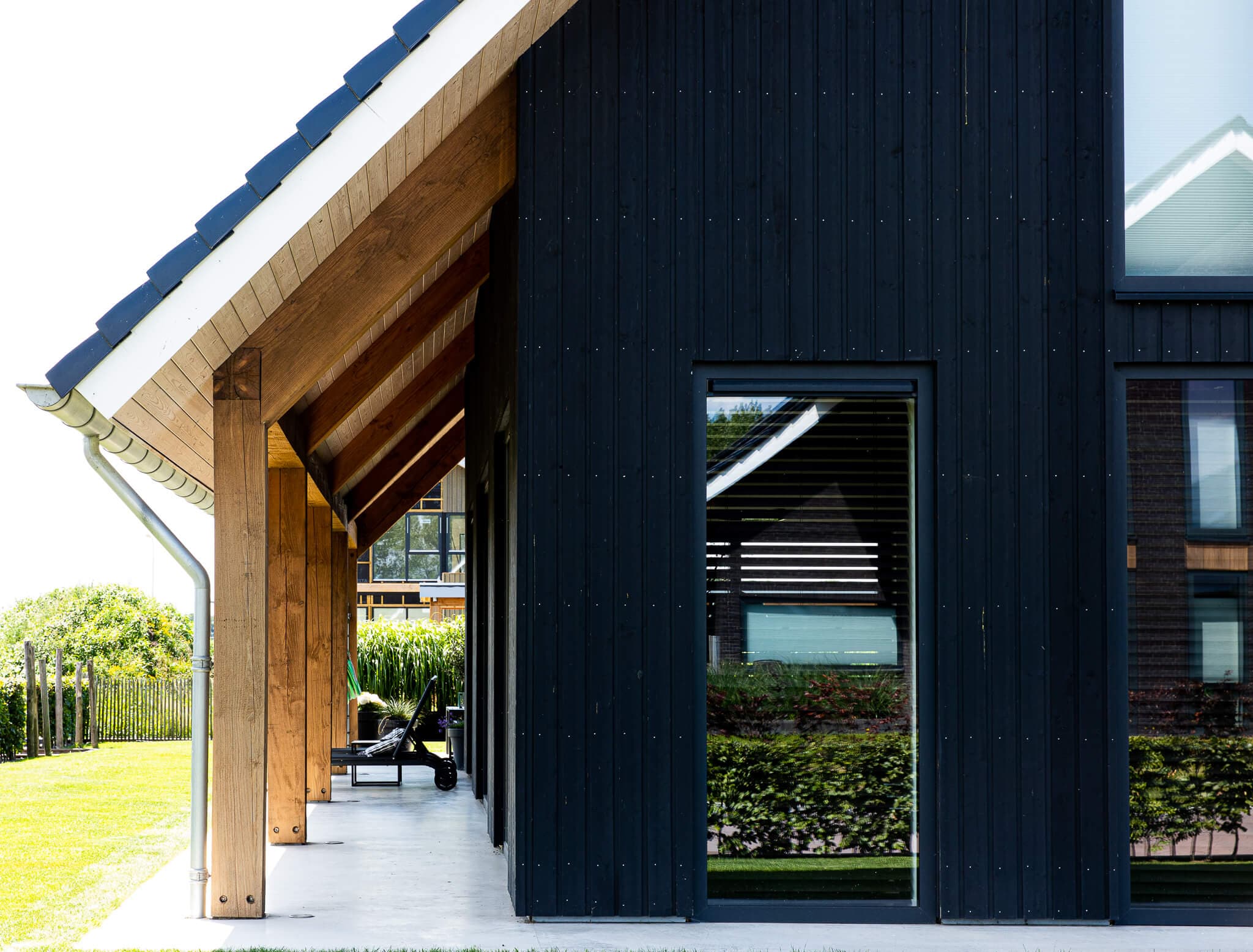 Schuurwoning in Wolvega met zwarte houten gevel, houten spanten en groot dakoverstek aan natuurgebied en water.
