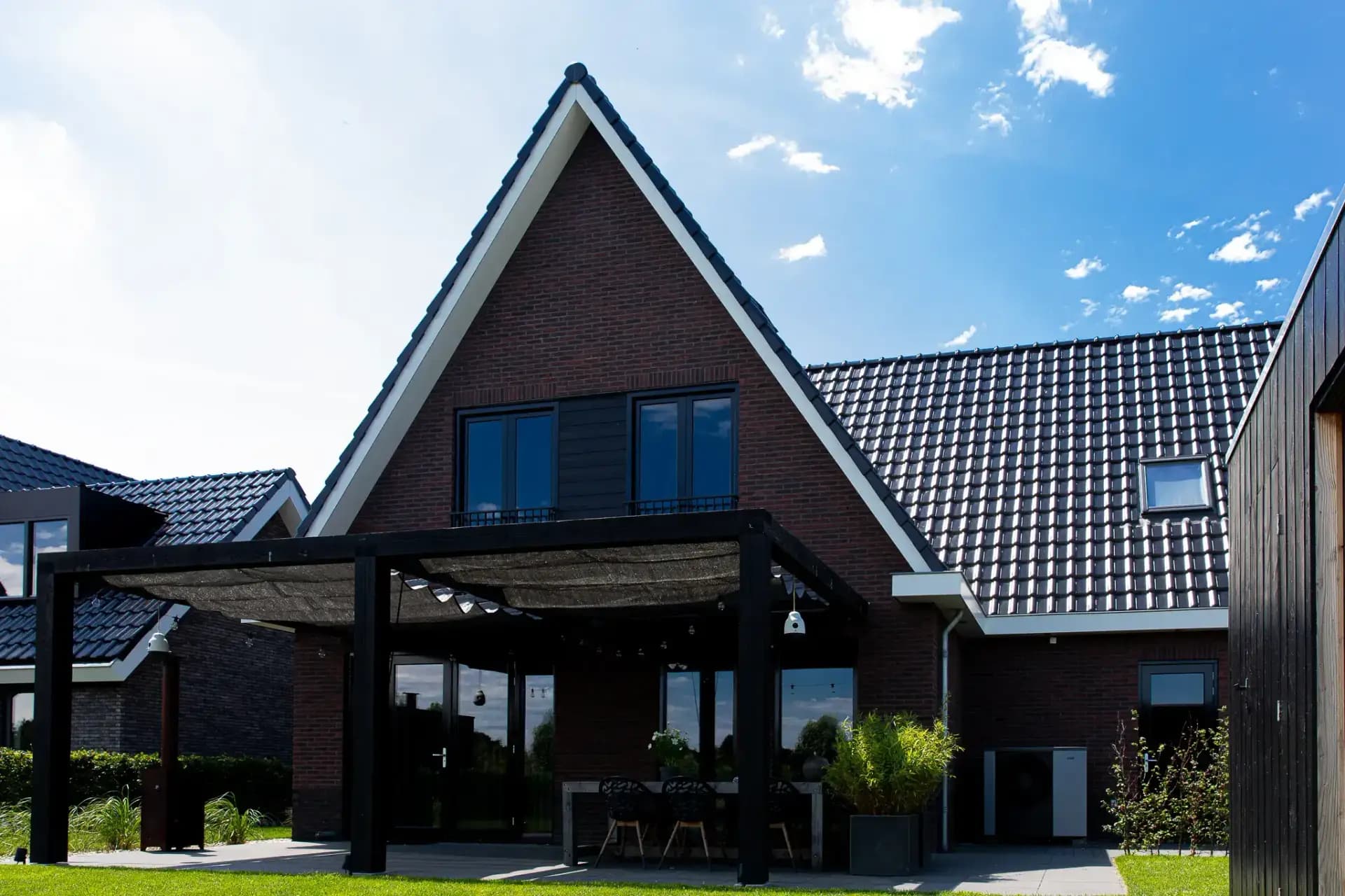 Traditionele T-kapwoning in Wolvega met klassieke materialen, een risaliet aan de tuinzijde en grote glasopeningen met uitzicht op het water.