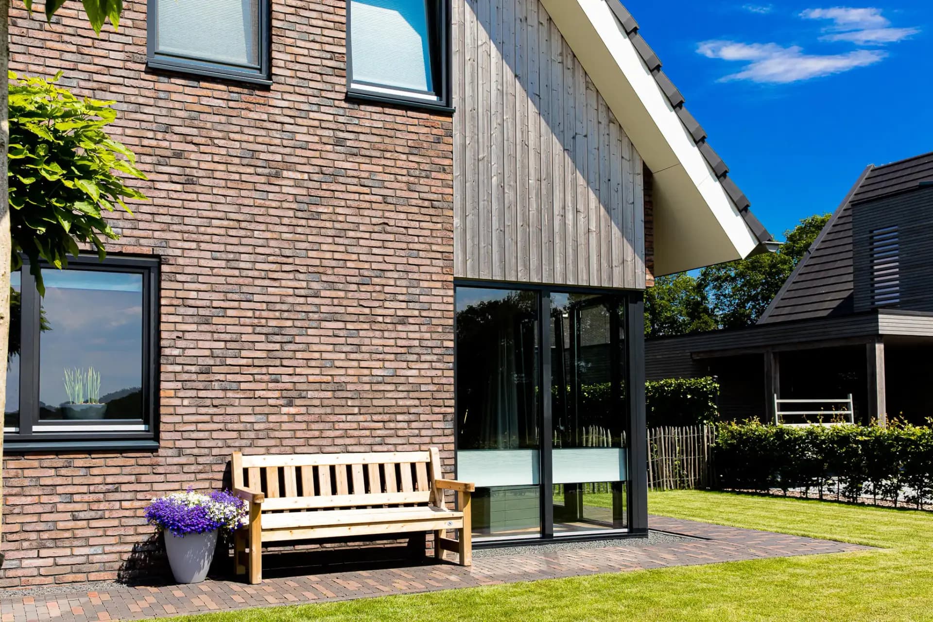 Parallelle kapwoning in Willemsoord met dubbele kapconstructie, twee nokken op één zakgoot, bruinrode baksteen en accenten in naturel hout.