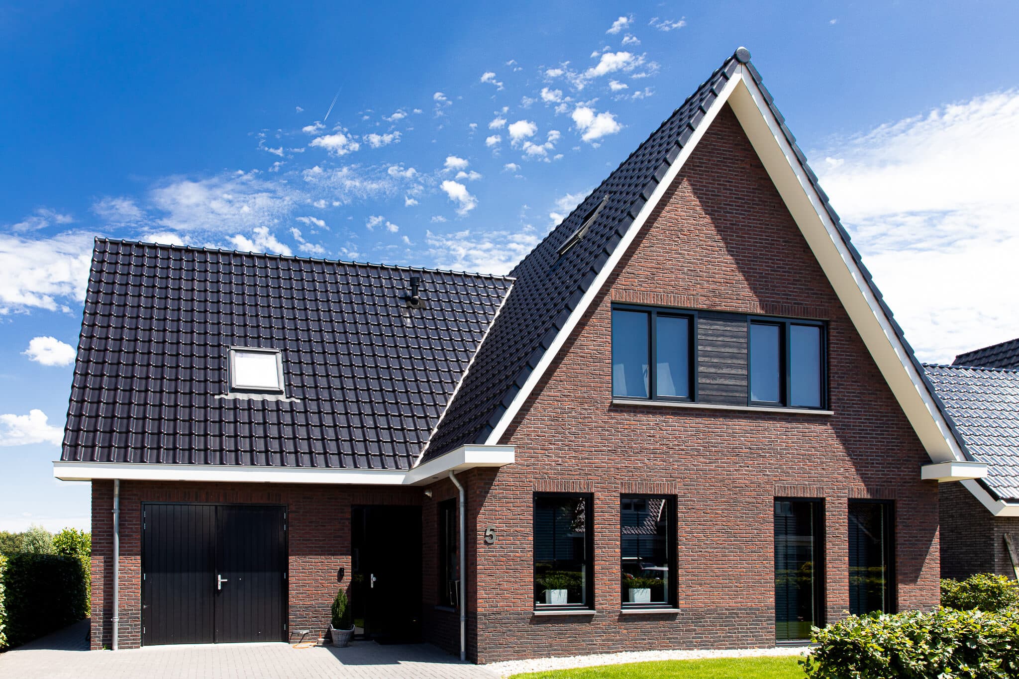 Traditionele T-kapwoning in Wolvega met klassieke materialen, een risaliet aan de tuinzijde en grote glasopeningen met uitzicht op het water.