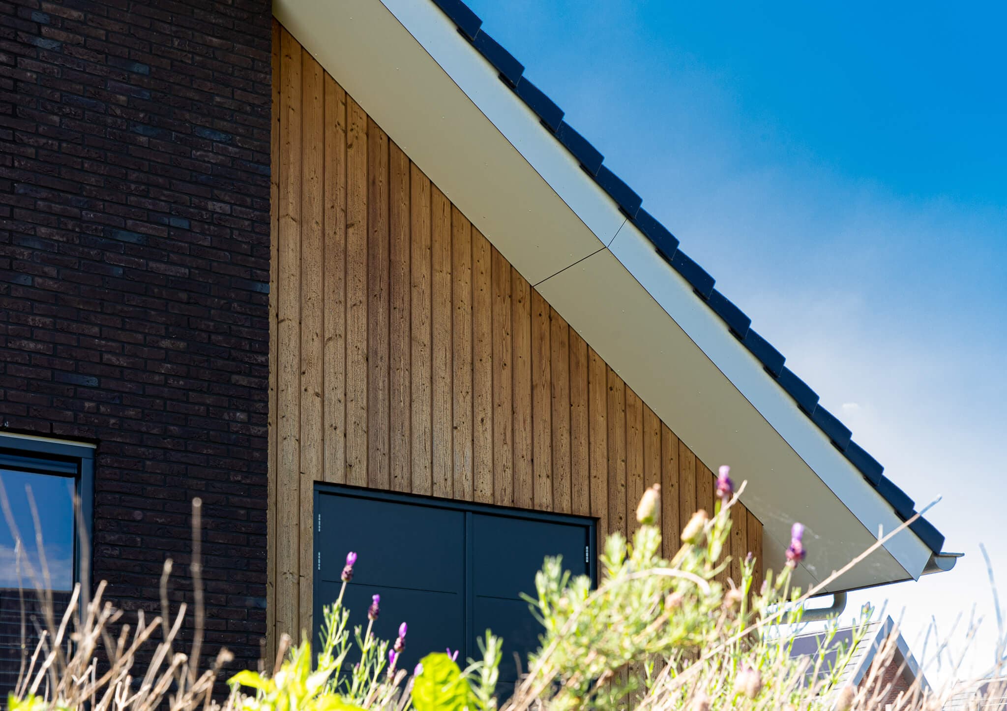 Vrijstaand modern woonhuis aan het Heideblauwtje in Wolvega (Lindewijk) met baksteen, houten accenten, leigrijze kozijnen en licht boeideel.