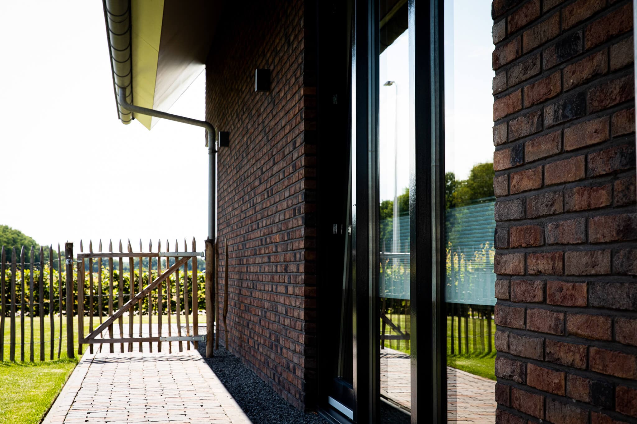 Parallelle kapwoning in Willemsoord met dubbele kapconstructie, twee nokken op één zakgoot, bruinrode baksteen en accenten in naturel hout.