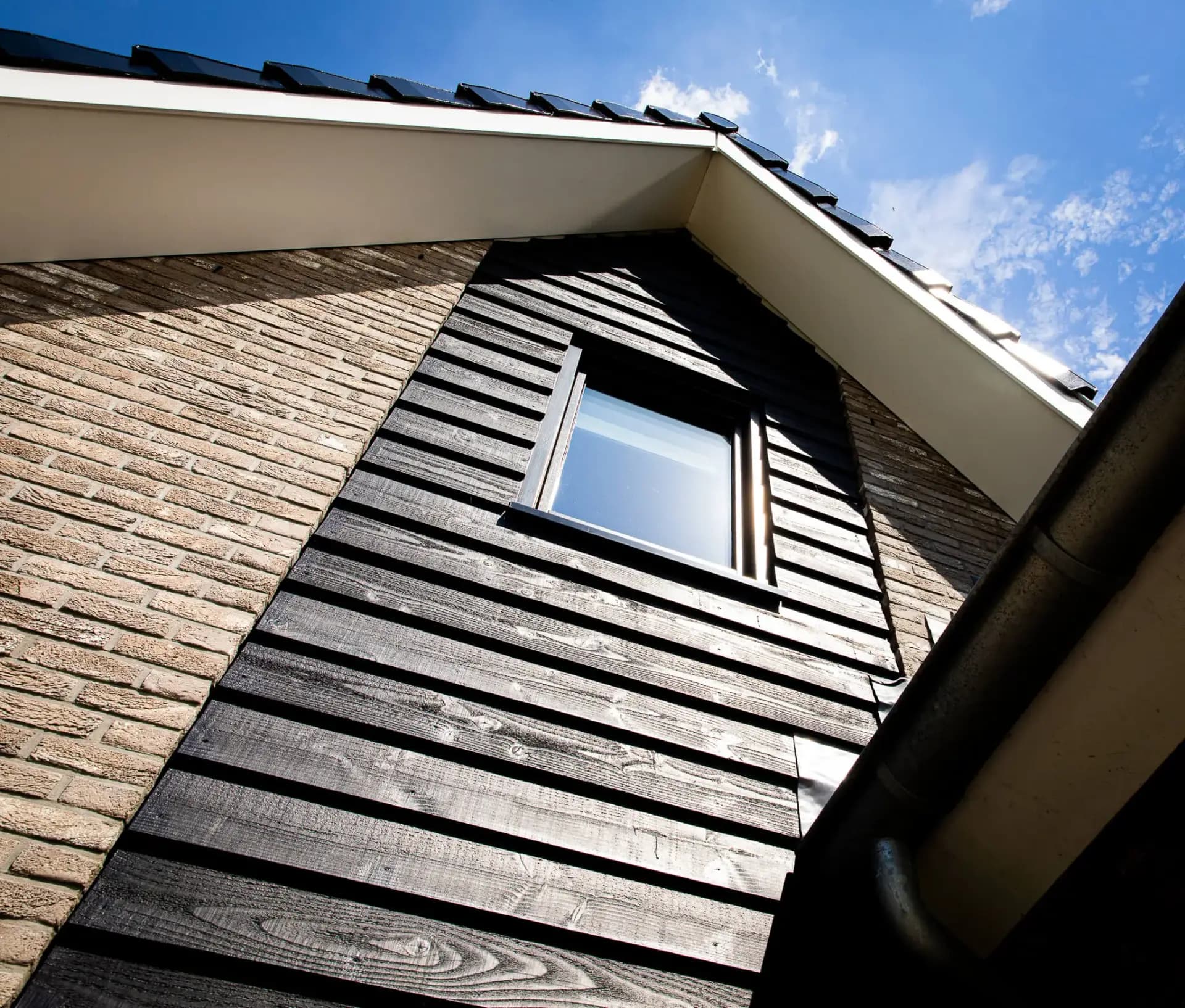 Woning in Willemsoord met dubbele kap, bronsgroen metselwerk en zwarte houten accenten — hedendaagse lintbebouwing.